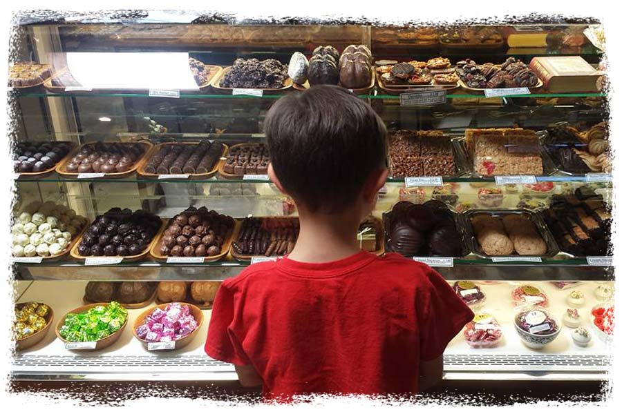 girl looking at chocolates and pastries in glass display case